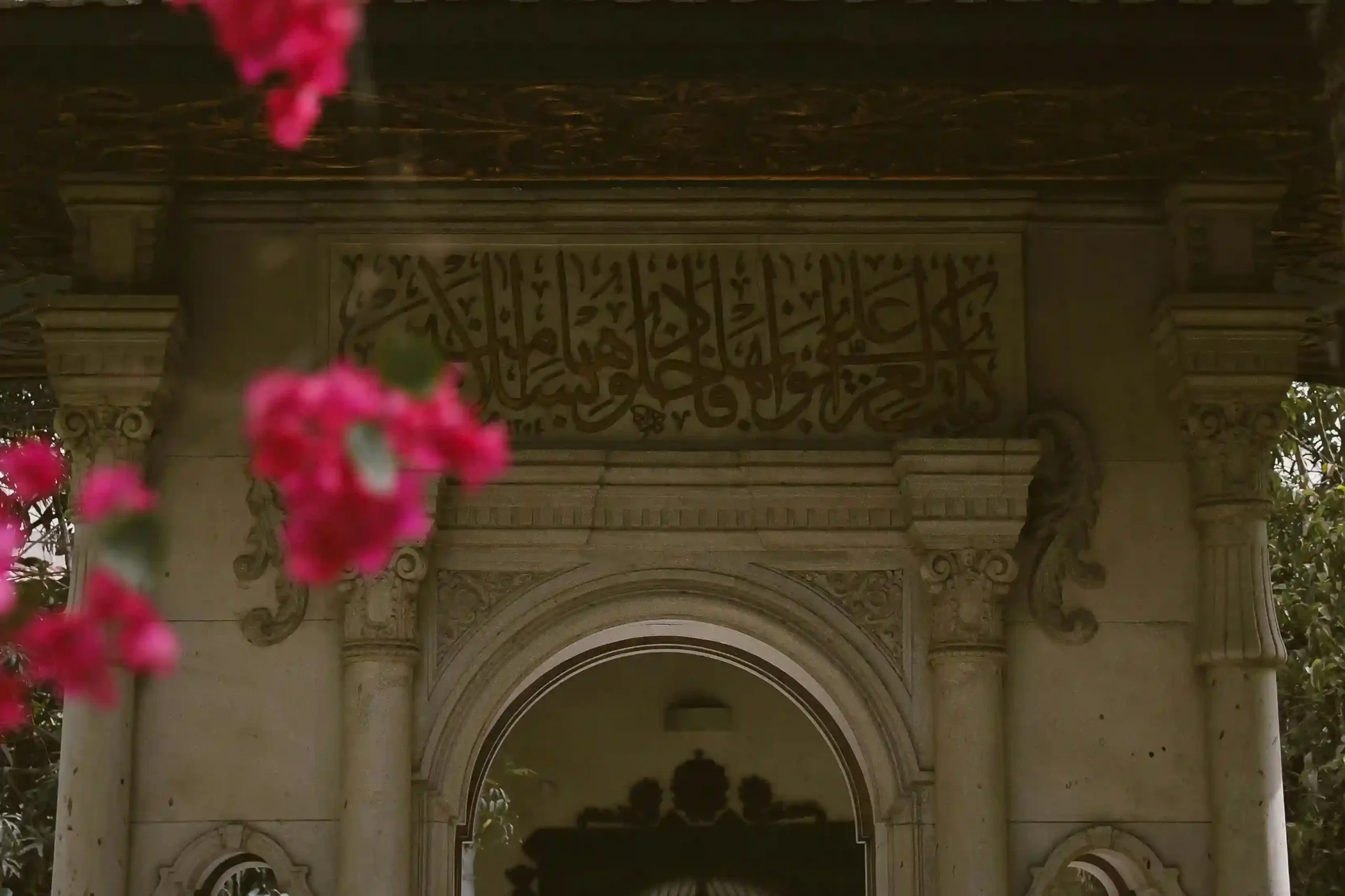 Entrada de una mezquita con caligrafía coránica y buganvilla, lugar de encuentro de la comunidad